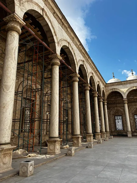 Bir sıra sütun ve kemer bir avlu hizasında. İskeleler mevcut ve gökyüzü görülebilir durumda..