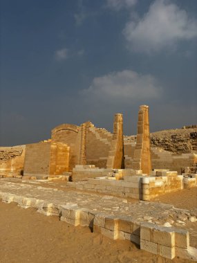 Eski Mısır kalıntıları, muhtemelen Saqqara. Bulutlu bir gökyüzünün altındaki taş yapılar. Tarihi konum.