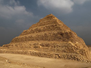 Mısır 'ın Saqqara kentindeki Djoser Piramidi. Bulutlu gökyüzüne karşı antik mimari.