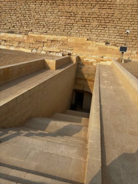 Tarihi bir yere giriş, muhtemelen bir mezar ya da piramit. Taş basamaklar karanlığa doğru iniyor. Eski mimari.