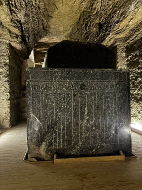 Büyük, karanlık taş bir lahitin olduğu bir mezarın içi. Karmaşık oymalar yapılmış, oyulmuş taş bir odaya yerleştirilmiş..