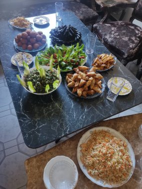 Masaya yerleştirilmiş çeşitli yemek malzemelerinin genel çekimi. Salatalar, kızarmış yiyecekler, soslar ve pilav da dahil..