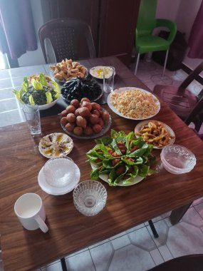 Salatalar, aperatifler ve tatlılar da dahil olmak üzere çeşitli yemek tabakları ile dolu bir masanın genel çekimi. Parlak, kapalı ortam.