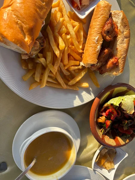 Yemek manzarası: sandviç, patates kızartması, çorba, salata. Altın ışık.