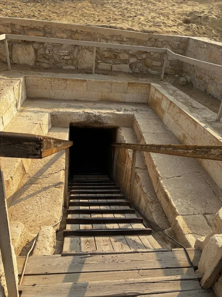 Taş ve ahşap merdivenleri olan bir yeraltı binasına giriş, muhtemelen kumlu bir yüzeyin altında bir mezar ya da antik bir alan..