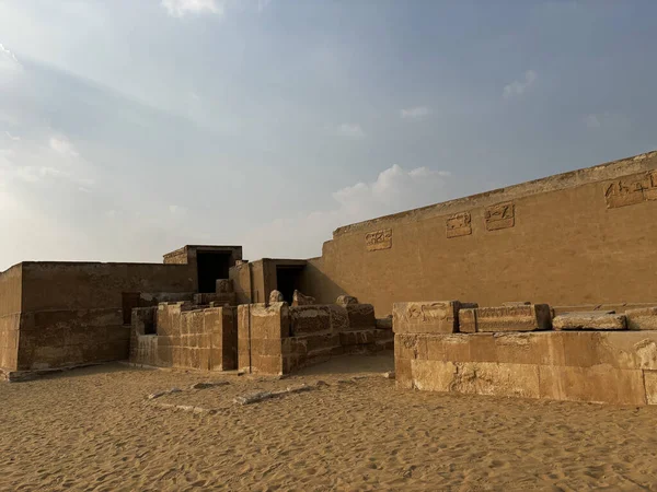 Eski Mısır yapısı / harabeleri hiyeroglifler ile, kumlu, çöl gibi bir ortamda hafif bulutlu bir gökyüzü altında.