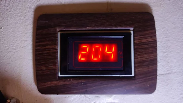 Tahta görünümlü bir panele gömülü dijital ekran, 402 sayısının parlak kırmızı parmaklarla gösterildiğini gösterir.