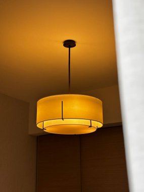 Aydınlatılmış, modern tavan lambası silindirik bir gölge, tavandan sarkan sıcak ışık.