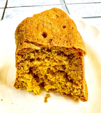 Beyaz bir tabakta ev yapımı altın sarısı kek. Pastanın biraz kaba bir dokusu var ve ortada konumlandırılmış..