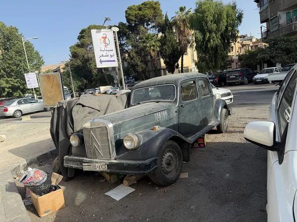 Eski, muhtemelen terk edilmiş, şehir caddesinde park edilmiş diğer araçların ve tabelaların yanına park edilmiş bir araba..