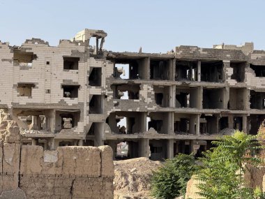 Savaşın yıktığı bina, ağır hasar görmüş, yıkımı ve çökmüş kısımları gösteriyor. Yapıdaki döküntüler görünür..