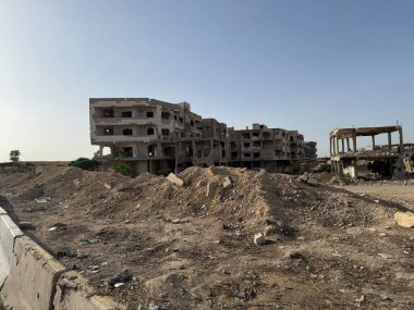 Savaşın yıktığı, bombalanan binalar enkaz ve ıssız arazinin ortasında berrak bir gökyüzünün altında. Yıkımın ve çatışmanın kanıtı.