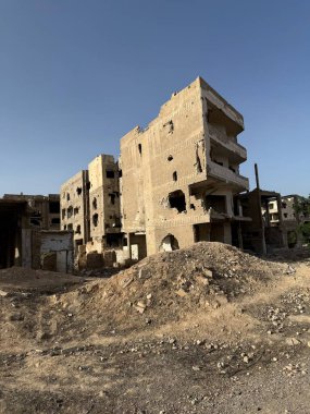 Muhtemelen bombalanan savaştan zarar görmüş bina, açık bir gökyüzüne karşı duruyor. Hasarlı cephe ve moloz görünür..