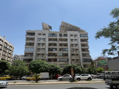 Araçlar ve ağaçlarla kentsel çevrede inşa edilmiş. Parlak, berrak gökyüzü.