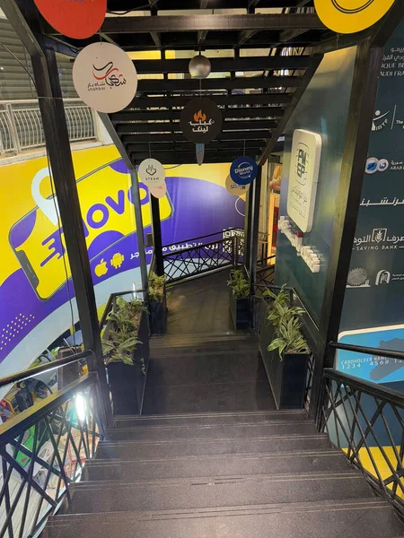 Dekoratif tabelalar ve bitkilerle dolu bir merdiven boşluğuna bakıyorum. Siyah metal parmaklıklar öne çıkıyor..