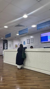 Resepsiyonda tesettür takan bir kadın. Personeli olan bir klinik ya da hastanenin iç görünümü.