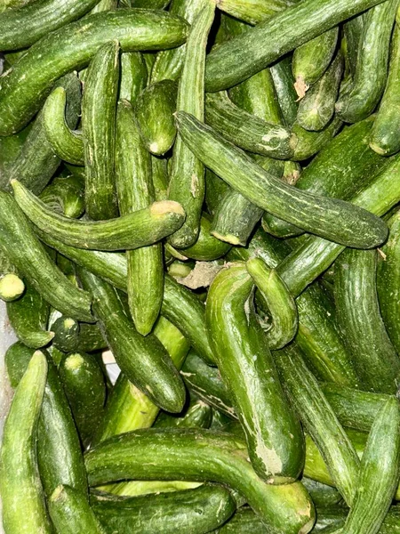 Bir yığın taze, yeşil salatalık. Salatalıklar küçük, değişik şekillerde ve yeşil tonlarda..