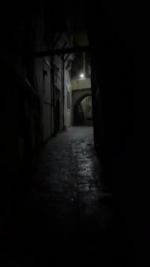 Karanlık, tuğla kaplı bir geçide alçak açılı bir bakış açısı. İçerideki ışık kaynağı. Kamera sanki dar bir alandan çıkıyormuş gibi yukarı çıkıyor..