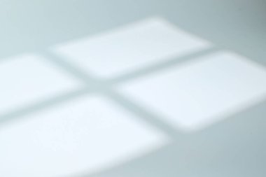 Yumuşak pencere ışığı beyaz bir yüzeye temiz bir gölge bırakıyor. Minimalist soyut arka plan ve doğal güneş ışığı. Modern tasarım düzeni, rahatlatıcı görsel kavramlar veya marka şablonları için mükemmel