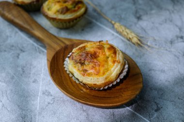 Ev yapımı mini tartlar, sıcak ve doğal bir arka planı olan ahşap bir kaşığa yerleştirilmiş. Yemek blogları, fırın reklamları ya da tarif çizimleri için mükemmel.