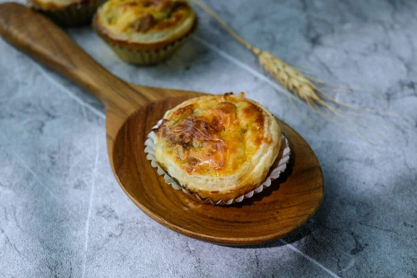 Ev yapımı mini tartlar, sıcak ve doğal bir arka planı olan ahşap bir kaşığa yerleştirilmiş. Yemek blogları, fırın reklamları ya da tarif çizimleri için mükemmel.