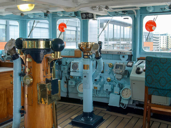 An immersive interior view of the Royal Yacht Britannia's historic bridge, showcasing intricate brass instruments and the ship's command center.