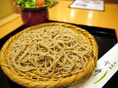 Otantik Japon Zaru Soba, soğuk karabuğday eriştesi, dokuma bambu sepetinde güzelce sunuluyor, yanında da küçük bir meze var..
