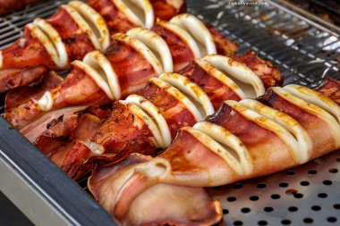 Taze ızgara mürekkep balığı halkaları kızgın bir metal ızgarada kahverengileşir, tezgahta sergilenir, Tayvan gece pazarının tadını ve dumanlı aromasını çağrıştırır..