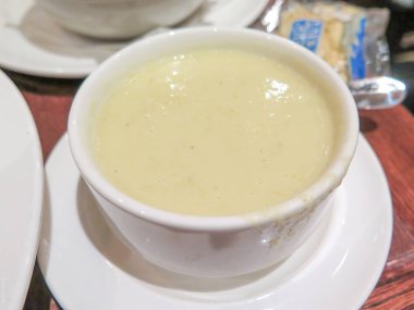 Sıcak, rahatlatıcı bir yakın plan kremalı patates ve pırasa çorbası kırsal bir ahşap masada, yumuşak ışıklandırmayla servis edilir..