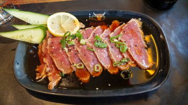 Limon, salatalık, yeşil soğan katılmış koyu susam sosuna bulanmış Japon usülü bir ton balığı tabağı..