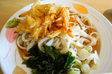 Canlı, soğuk bir udon tabağı beyaz desenli bir kasede servis edilir. Üstünde çıtır çıtır sebzeler, yeşil soğanlar, wasabi ve ahşap bir masanın üzerindeki yosun vardır..