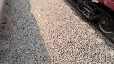 Bangladeş 'in kırmızı tren vagonunun ve tekerlek sisteminin solunda başka bir tren olan bir istasyondaki görüntüsünü kapatın.