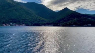 Huzurlu ve sakin bir manzara, yemyeşil tepelerin arasında güneş ışığını yansıtan güzel bir dağ gölü tasvir ediyor.