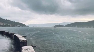 Huzurlu ve sakin bir deniz manzarasının tadını çıkarın. Hafif dalgalar ve bulutlu, karamsar gökyüzü, rahatlamak için ideal.