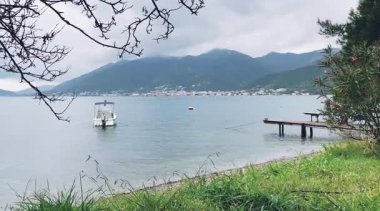 Huzurlu bir göl manzarası, küçük bir tekne, görkemli dağlar, ve bulutlar, rahatlama ve huzur için mükemmel.