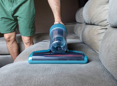 Adam koltukta elektrikli süpürge kullanıyor..