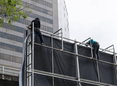 İşçiler reklam panoları yüklemek için reklam panolarına tırmanıyorlar