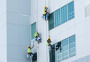 Boyacı binanın üzerine boya serpiyor.