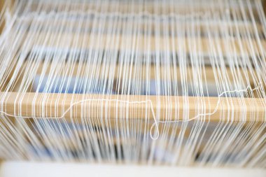 Beyaz warp iplikleri, bir tekstil dokuma tezgahındaki ahşap tezgah tezgahına eşit şekilde gerilir..