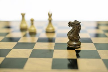 Bir siyah satranç şövalyesi keskin odaklı bir satranç tahtası üzerinde düzensiz durur, bulanık beyaz parçalar ise arka planda dikey kalır, düzenli bir sistem içinde kural kırmayı sembolize eder.