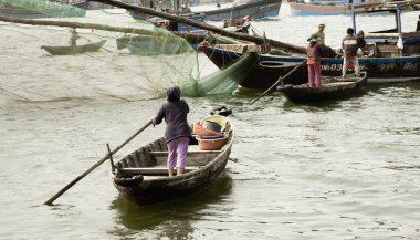 Da Nang, Güney Vietnam - 26 Aralık 2013 Vietnamlı kadın balıkçı teknesine doğru kürek çekiyor.
