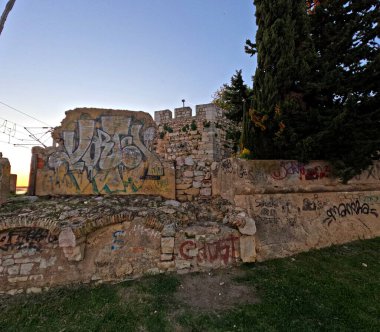Günbatımında Faro, Algarve, Portekiz 'deki limanın yanında duvar yazısı olan eski taş duvar..