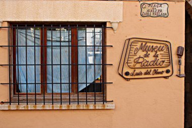 Roc de Sant Gaieta 'daki Luis del Olmo Müzesi, Roda de Bera, Tarragona, İspanya. Sıcak renkli bir Akdeniz duvarında eski bir radyo ve klasik bir mikrofon şeklinde klasik bir tabela, İspanyol radyo tarihinin kültürel anısına..