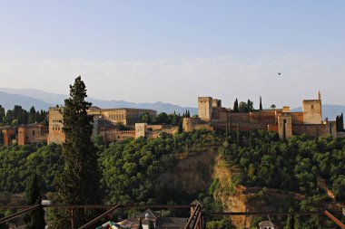 Mirador de San Nicolas 'tan Granada' daki Alhambra 'nın panoramik manzarası arka planda belli belirsiz Sierra Nevada dağları ile yemyeşil orman yamaçlarının üzerinde yükselen Nasrid saraylarını, kuleleri ve antik savunma duvarlarını gözler önüne seriyor..