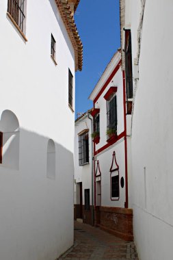 İspanya, Cija 'da, beyazlatılmış Endülüs evleri, dövmeli demir pencere ızgaraları ve kırmızı mimari aksanları ile büyüleyici dar bir ara sokak. Bu tarihi Endülüs şehrinin barışçıl atmosferini ve geleneksel karakterini yakalıyor.