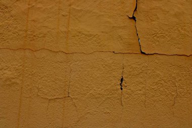 Kaba yüzey ve yatay çatlak çizgilere sahip çatlak sarı alçı duvar dokusu, yıpranmış ön cephe ayrıntıları, tasarım projeleri için soyut mimari arka plan ideali, kentsel dokular, minimum bileşimler ve malzeme referansları
