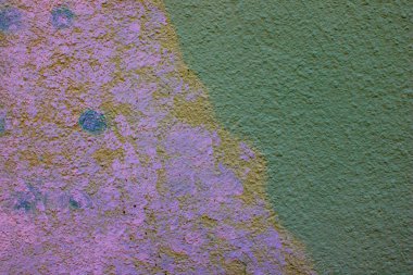 Pembe boya kalıntıları ve pürüzlü desenli yüzeyi olan aşınmış yeşil sıva duvarları katmanlı renkleri ve aşınmayı gösteren yaşlandırılmış dış sıva, sıkıntılı boya ile soyut mimari arka plan, kentsel çürüme dokusu 