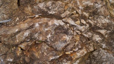 Yüksek oranda parçalanmış bir kaya yüzeyinin detaylı bir yakın çekimi, açısal olarak kahverengi ve beyaz taş parçaları, engebeli ve karmaşık bir jeolojik doku oluşturur..