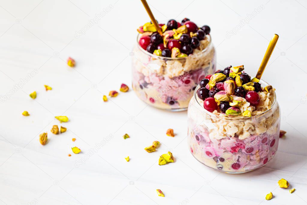 Overnight oatmeal with berries and nuts in a jar on a white background. Healthy breakfast concept.