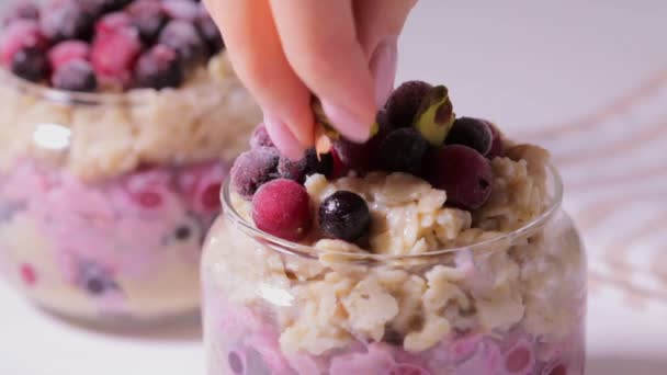 Overnight oats with berries and nuts in a jar on white background, copy space. Healthy breakfast concept. — Stock Video